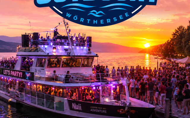 Sommerabend an der Ostbucht am Wörthersee mit DJ, Saxophon und tanzenden Gästen bei Sonnenuntergang.