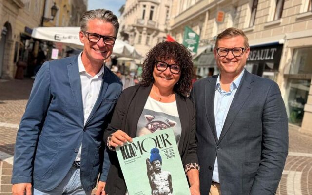 Menschen besuchen Geschäfte in der herbstlichen Klagenfurter Innenstadt.