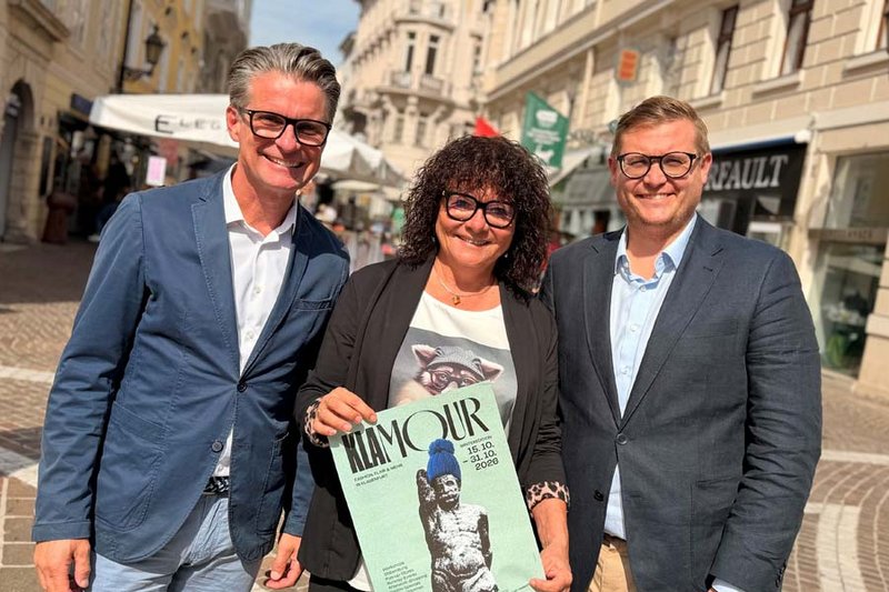 Menschen besuchen Geschäfte in der herbstlichen Klagenfurter Innenstadt.
